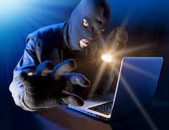 A criminal wearing a balaclava and holding a torch has access to a laptop